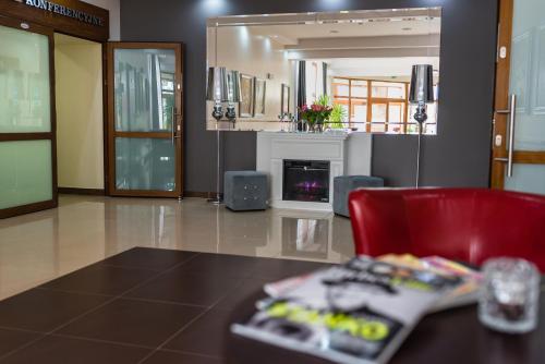 a living room with a red chair and a fireplace at Hotel Polonia in Biała Podlaska