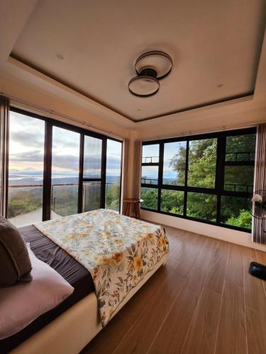 a bedroom with a bed and large windows at The Hillside Villa Tagaytay in Laurel