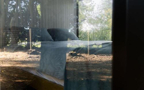 a glass window with a bed in a yard at Pine Nut Corner by Tiny Away in West Melton