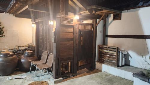 a room with two chairs and a wooden wall at Hanok1942 in Daegu