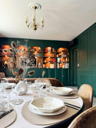 a dining room with a table with plates and wine glasses at Green Library, appartement 6 personnes à Nemours in Nemours