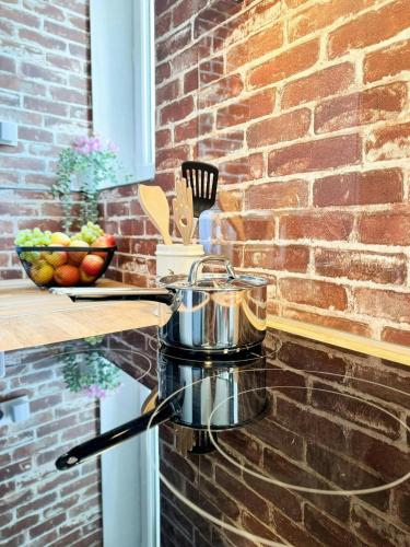 a pot sitting on a stove next to a brick wall at Green Library, appartement 6 personnes à Nemours in Nemours