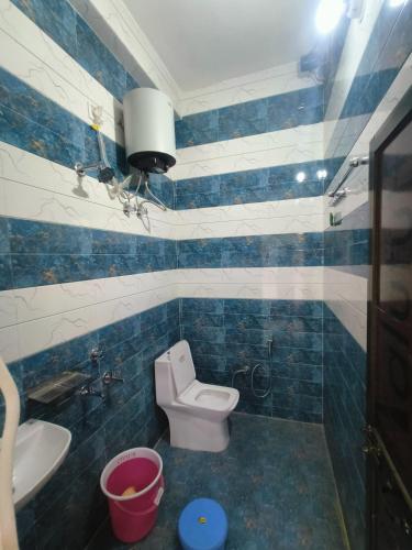 uma casa de banho em azulejos azuis com um WC e um lavatório em Parth homstay em Ayodhya