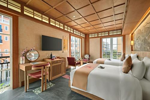 a hotel room with two beds and a desk and a television at Sakurakyo Hotel & Spa Phu Quoc - Free Hon Thom Island Waterpark Cable Car Until 15 December 2025 in Phu Quoc