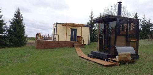 a tiny house with a porch and a deck with a stove at Raadivere Põllupeegel in Raadivere
