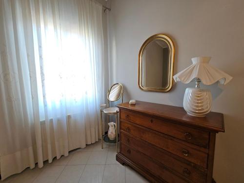 una camera da letto con una cassettiera con uno specchio e una lampada sopra di Casa Orchidea a La Spezia a La Spezia