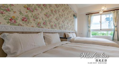 two beds in a bedroom with floral wallpaper at 微風星語名宿WindStar B&B in Jian