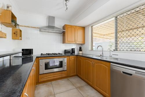 a kitchen with wooden cabinets and a sink at Cosy Corner Retreat by SwanBnB Management in Hamilton Hill