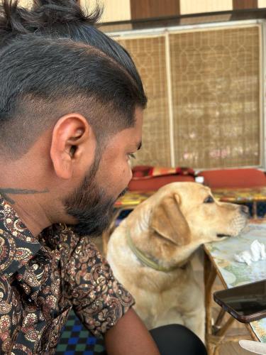 a man sitting next to a dog at a table at Karma Hostel in Khajurāho