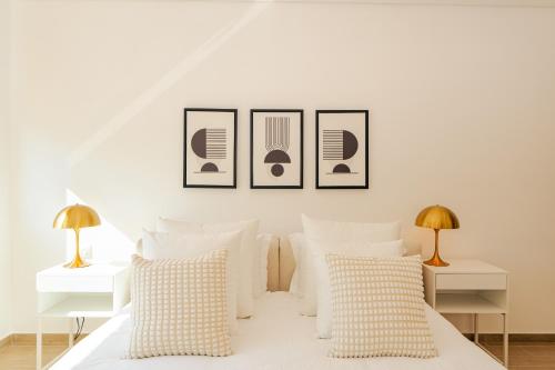 a bedroom with a white bed with three pictures on the wall at Voyage 2 Bedroom In Mayan With Beach Access in Abu Dhabi