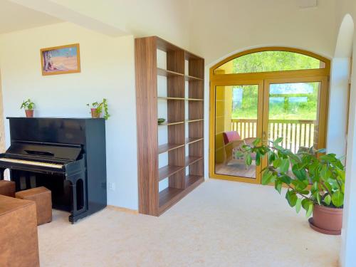 a living room with a piano and a balcony at Villa Beelvita&Jacuzzi in Bielovce