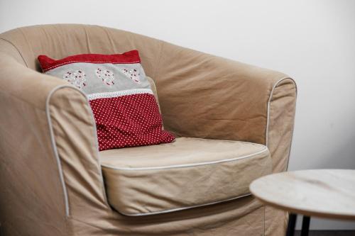 a brown chair with a red and white pillow on it at Gite de l'école des Gourmands in Moulin-Neuf
