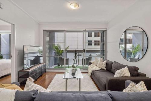 a living room with a couch and a mirror at Darling Harbour 2BR Retreat with Spacious Balcony in Sydney