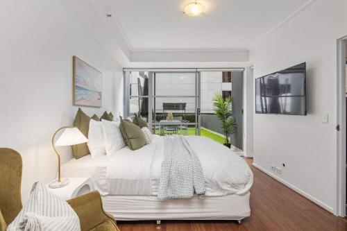 a white bedroom with a large bed and a balcony at Darling Harbour 2BR Retreat with Spacious Balcony in Sydney