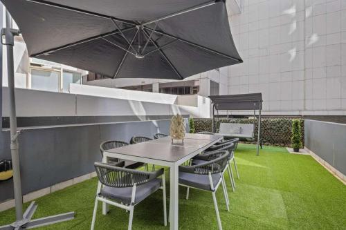 a table and chairs with an umbrella on a patio at Darling Harbour 2BR Retreat with Spacious Balcony in Sydney