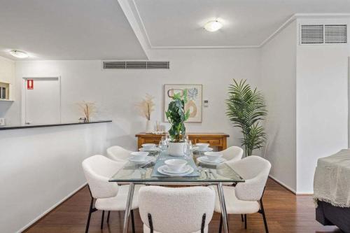 a dining room with a glass table and white chairs at Darling Harbour 2BR Retreat with Spacious Balcony in Sydney