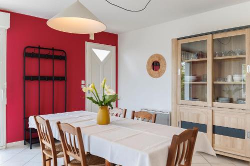 une salle à manger avec une table blanche et des murs rouges dans l'établissement L'escapade de Sauvagnac, à Libourne
