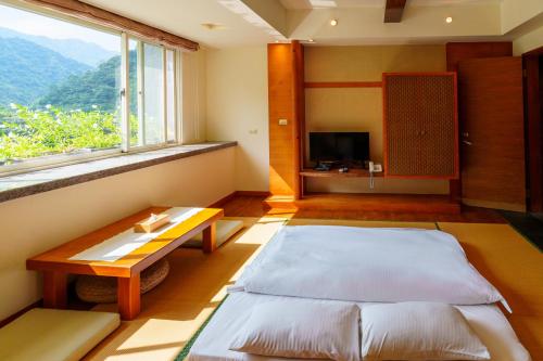 a bedroom with two beds and a table and a window at Spring Spa Hotel in Wulai