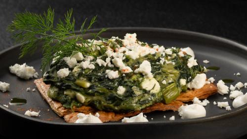 a piece of bread with cheese and vegetables on a plate at Aeolos Resort in Mýkonos City