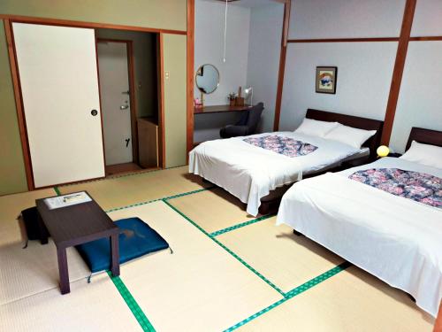 a hotel room with two beds and a table at いやし亭 心空 in Naka