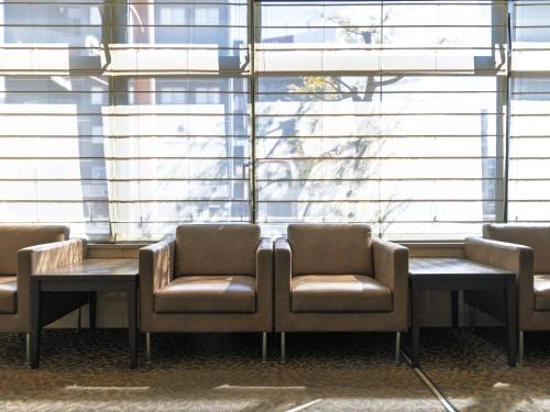 a waiting room with chairs and a table and windows at Nishitetsu Inn Tenjin in Fukuoka