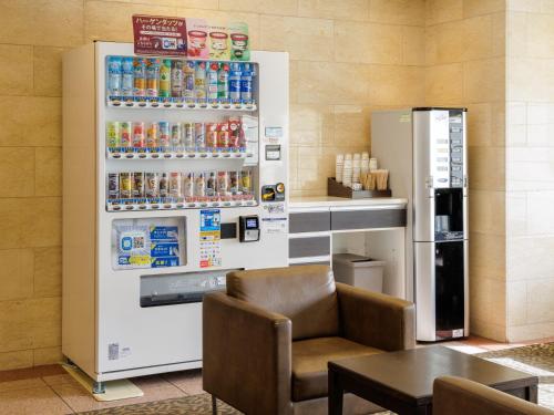 a soda machine in a restaurant with a chair and a table at Nishitetsu Inn Tenjin in Fukuoka