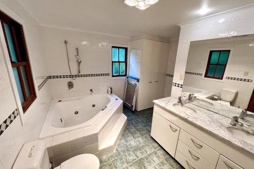 a large bathroom with a tub and a sink at Imis Cottage in Katoomba
