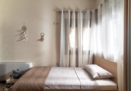 a bedroom with a bed and a window with curtains at Silva Luxury House in Mires (South Crete) in Moírai