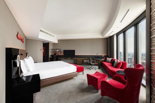 a hotel room with a bed and red chairs at Conrad Osaka in Osaka