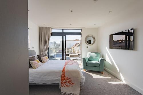 a bedroom with a bed and a chair and a balcony at Bun Penny Apartment by Keepers Cottages in Herne Bay