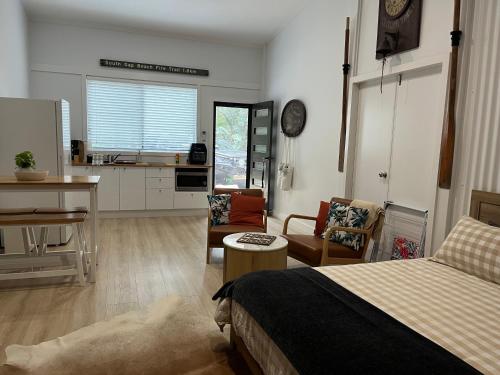 a bedroom with a bed and a kitchen with a table at South West Rocks Gap Beach Studio in Arakoon