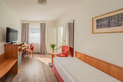 a hotel room with a bed and a table and chairs at Best Western Queens Hotel Pforzheim-Niefern in Pforzheim