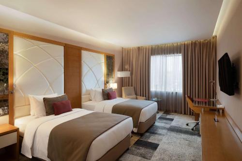 a hotel room with two beds and a television at Ramada by Wyndham Erbil Gulan Street in Erbil