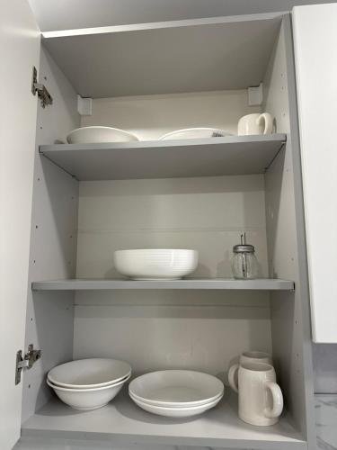 ein weißer Schrank mit Tellern und Schüsseln darin in der Unterkunft Уютные 1комнатные апартаменты на Казииту in Oral