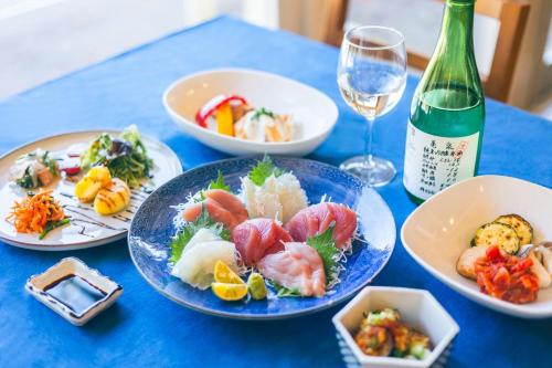 a blue table with plates of food and a bottle of wine at Pension Shishikui in Shishikui