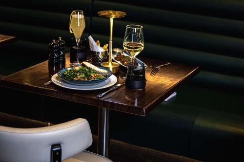 a table with a plate of food and glasses of wine at The Westminster London, Curio Collection by Hilton in London