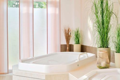 a white tub in a room with potted plants at Best Western Plus Hotel Papenburg in Papenburg
