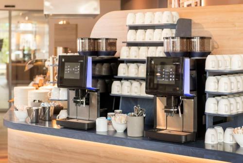 a coffee shop counter with machines on a shelf at Best Western Plus Hotel Papenburg in Papenburg