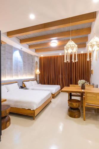 a bedroom with two beds and a wooden table at Chiu Chiu Resort Đảo Phú Quý in Cu Lao Thu