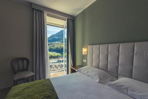 a bedroom with a bed and a large window at Hotel Due Palme in Mergozzo