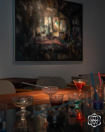 a table with glasses on it with a painting on the wall at Amanaki Saigon Boutique Hotel in Ho Chi Minh City