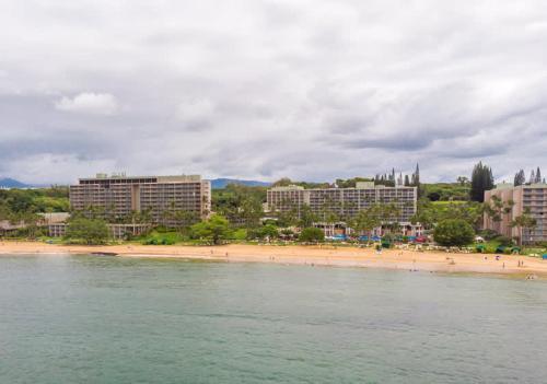 a beach with a group of people and buildings at Beachfront Bungalow Walk to Ocean & Restaurants in Lihue