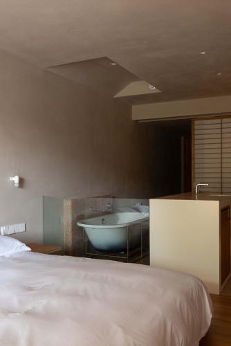 a bedroom with a bed and a tub and a sink at Rakuhotel in Wenzhou