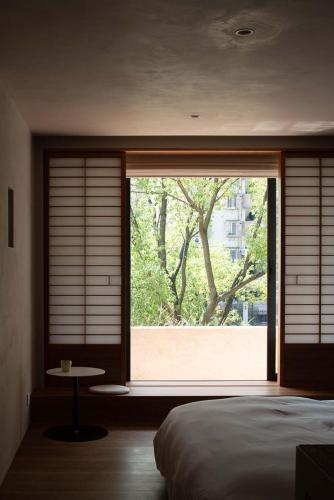 a bedroom with a large window with a tree outside at Rakuhotel in Wenzhou