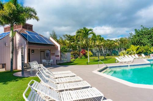 a group of white lounge chairs next to a swimming pool at Beachfront Bungalow Walk to Ocean & Restaurants in Lihue