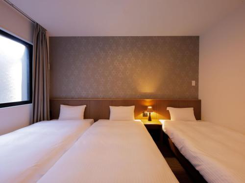 a room with two beds and a table and a window at Smart Place Inn Kyoto Nijojo Horikawa in Kyoto