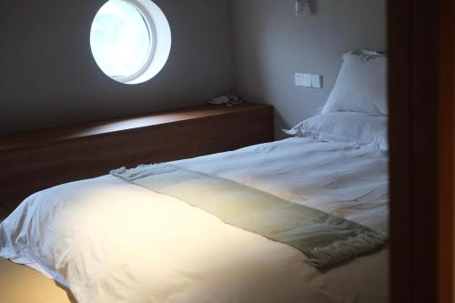 a bedroom with a white bed with a window at Rakuhotel in Wenzhou