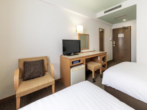 a hotel room with a desk with a tv and a chair at Nishitetsu Inn Tenjin in Fukuoka