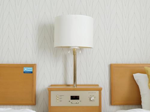 a lamp on a night stand next to a bed at Nishitetsu Inn Tenjin in Fukuoka