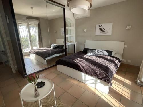 une chambre avec un lit, un miroir et une table dans l'établissement Villa 140 m2 4 étoiles - parking - wifi - clim - piscine, à Roquebrune-sur Argens